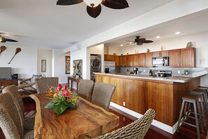 A modern kitchen with wooden cabinets, a central island, and bar stools.