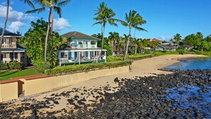 A beachfront property with a house, a pool, and palm trees. - Hale Nalu - Beachfront Home Steps from Baby Beach with Spa/AC! (Koloa)