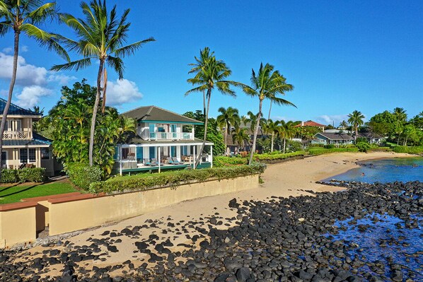 A beachfront property with a house, a pool, and palm trees. - Hale Nalu - Beachfront Home Steps from Baby Beach with Spa/AC! (Koloa)