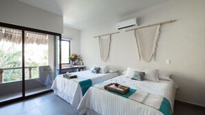 Une chambre d’hôtel avec deux lits, une grande fenêtre, un ventilateur de plafond et une vue sur des palmiers.