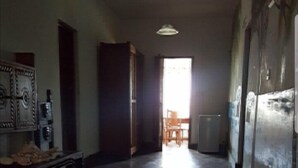 Una habitación amplia con techo alto, piso de madera y vista al exterior a través de un vano.