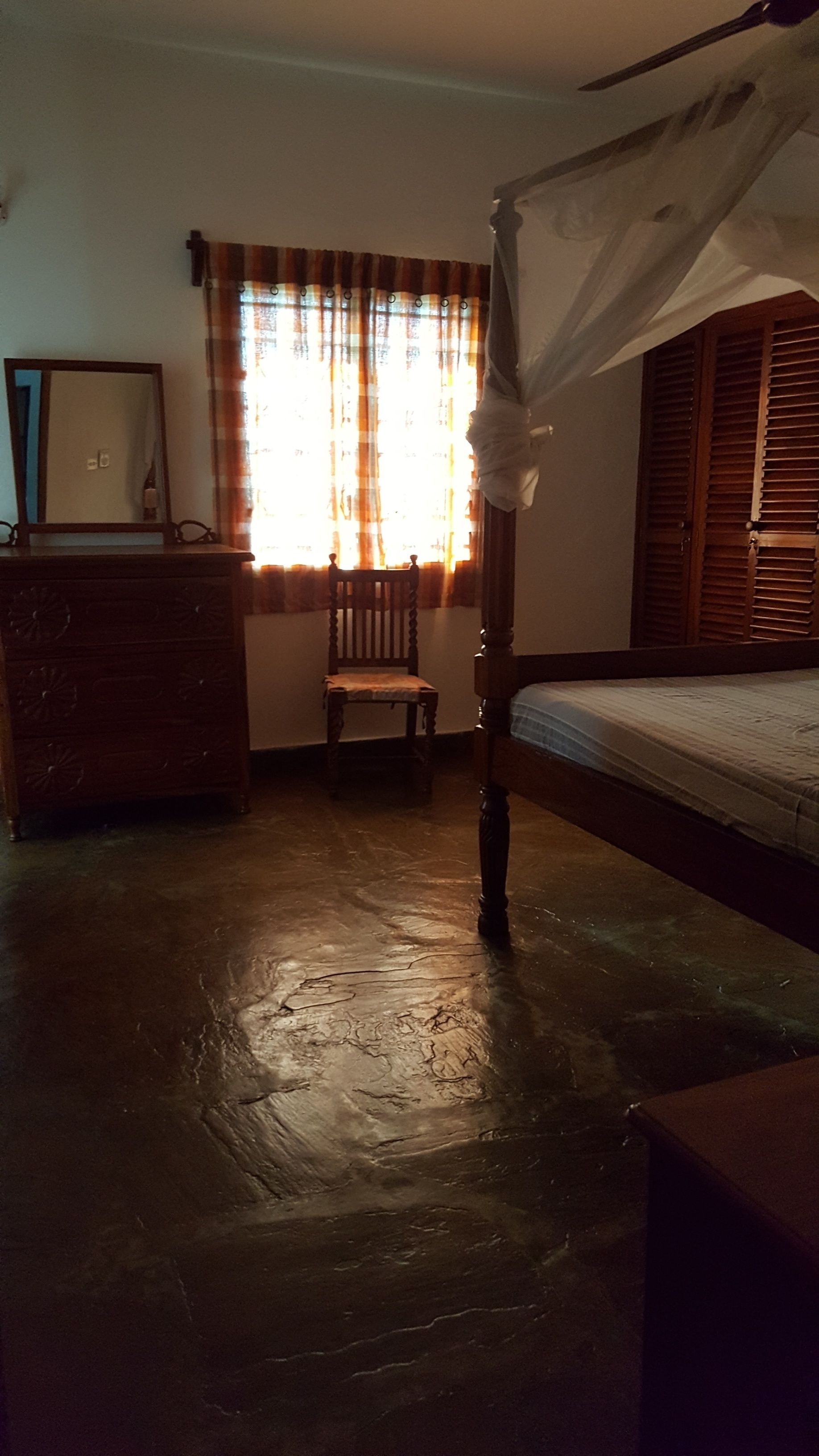 Un dormitorio con una cama de madera, un aparador de madera, una silla y una ventana con cortinas.
