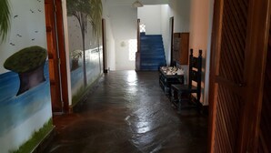 Un pasillo con piso mojado, una escalera y una pared con un mural de un árbol.
