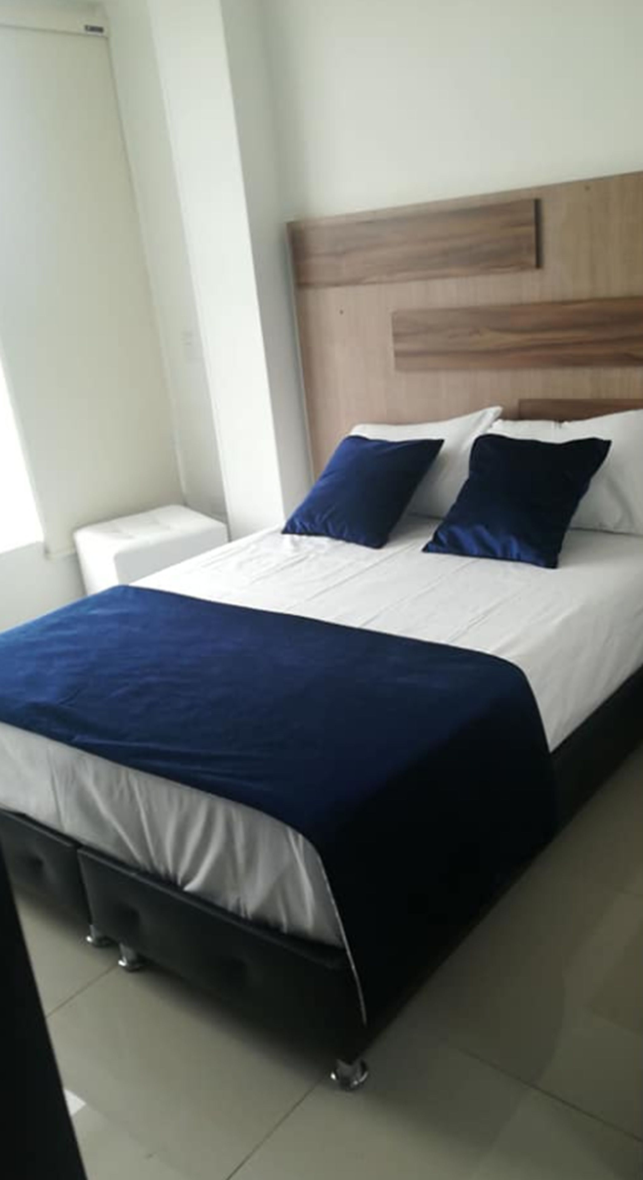 A bed with a wooden headboard, white bedding, and a blue accent.