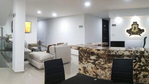 Una sala de estar moderna con una barra de mármol, una escalera y un sofá.