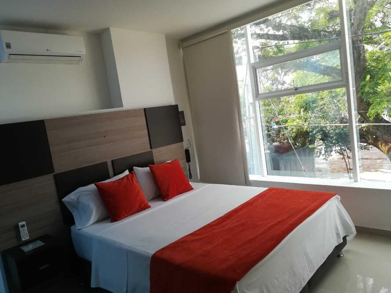 Habitación de hotel con cama, mesita de noche, teléfono y ventana con vistas a zonas verdes.