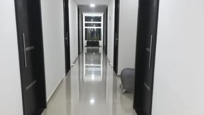 Un pasillo largo y estrecho con pisos de baldosas brillantes y puertas negras a ambos lados.