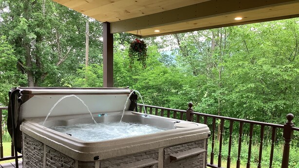 Un bain à remous sur une terrasse en bois, avec vue sur une forêt.
