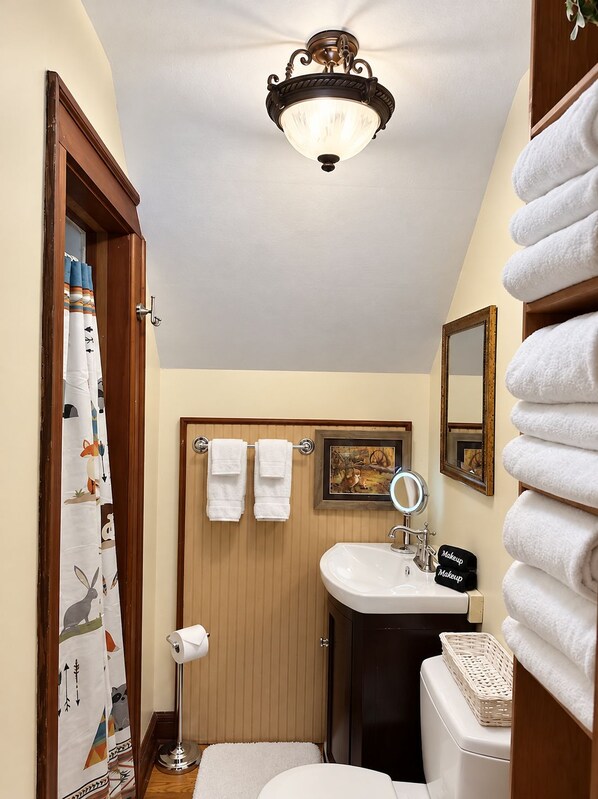 A bathroom with a wooden door, a white sink, a mirror, and a towel rack with two towels. - Red Fox Townhouse Private Hot Tub Near Skiing (Windham)