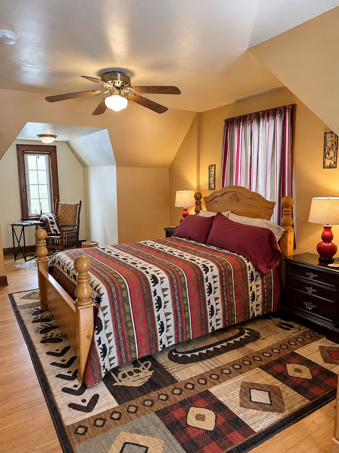 A bedroom with a wooden bed, a ceiling fan, a window with curtains, and a patterned rug.