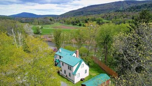 Une maison dotée d’un toit végétalisé, entourée d’une végétation luxuriante et avec des collines en arrière-plan.