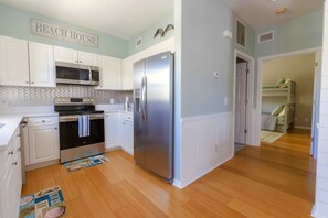Kitchen with microwave, oven, and refrigerator, adjacent to a bedroom with a bunk bed.