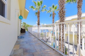 Stroll along the paved corridor, lined with a white railing, to a charming balcony surrounded by palm trees.