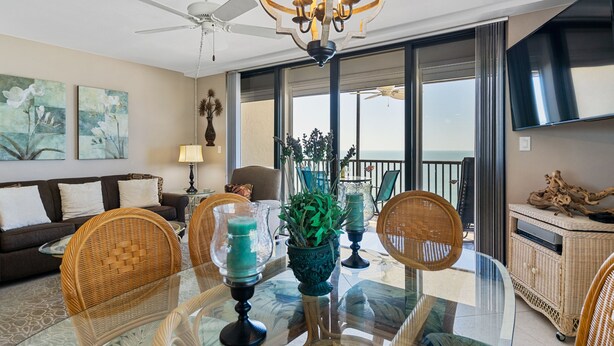A modern living room with a glass dining table, wicker furniture, and a balcony with a view. - Beautiful, updated, oceanfront views!  Gorgeous unit! (Marco Island)