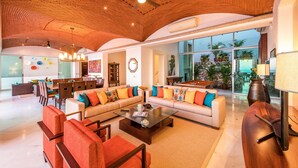 A spacious living area with a high ceiling, a pool table, and a view of the outdoors.