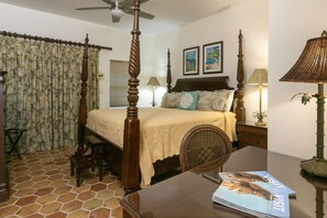 Un dormitorio con cama con dosel, una mesita de noche de madera, una lámpara y una revista sobre la mesa.