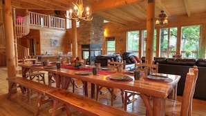 Un comedor de madera con una mesa larga, bancos y una chimenea.