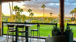 A covered outdoor seating area with a view of a golf course and palm trees. - Spectacular Views! Heated Pool. Game Room. Private. Spacious. (Fountain Hills)