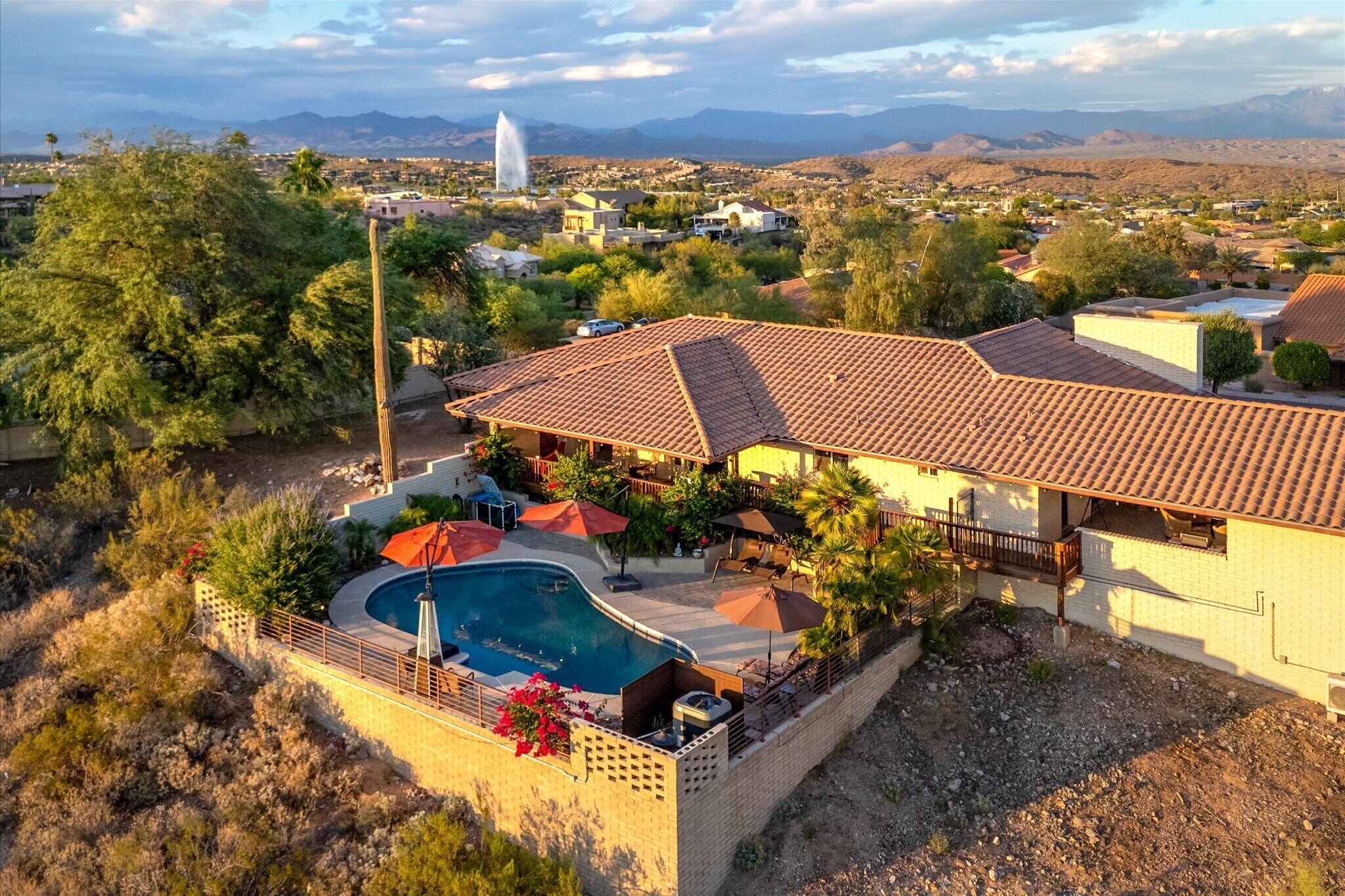 A residential property with a swimming pool, patio, and views of a mountainous landscape.