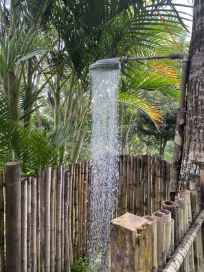 A bamboo fence with a waterfall feature in a lush, green environment. - Summer house, surrounded by trees, rural setting with city amenities. (Petrópolis)