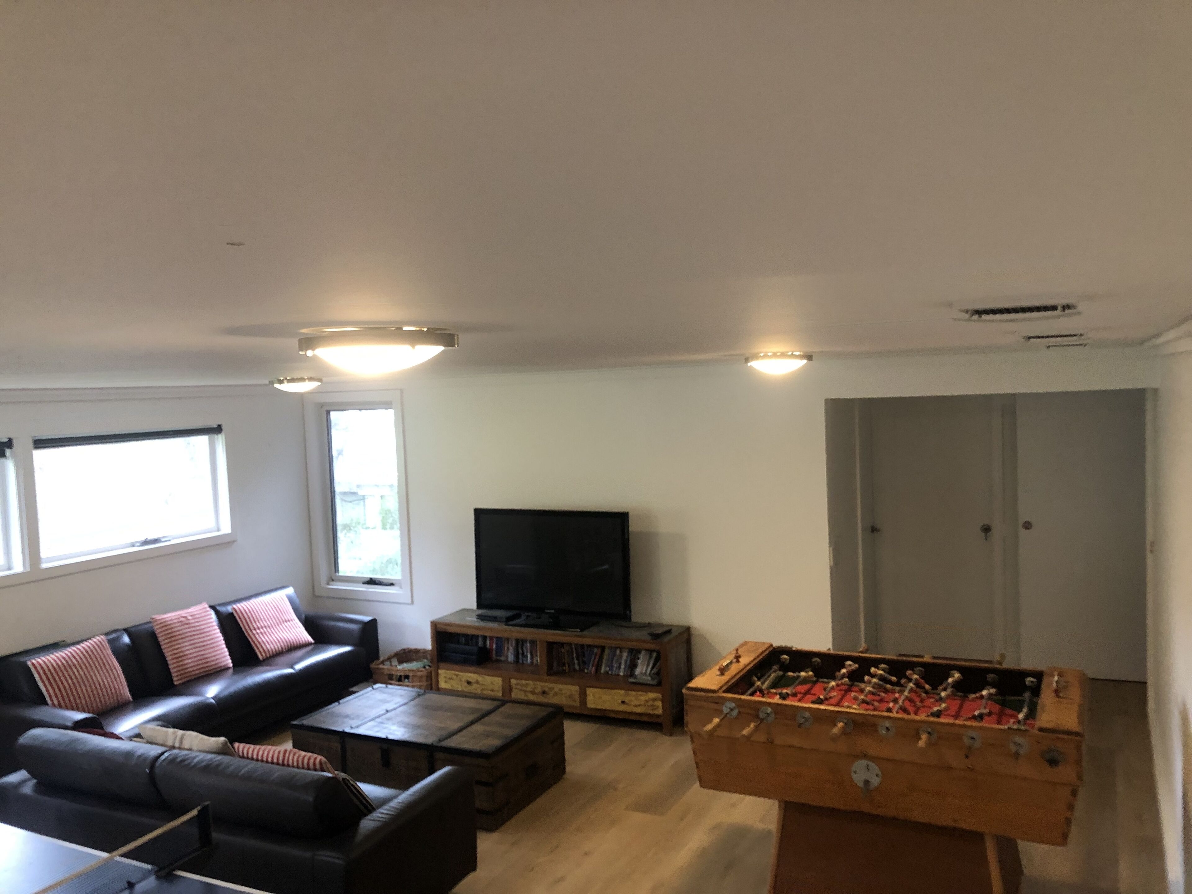 A living room with a sofa, a coffee table, a television, a bookshelf, and a foosball table.