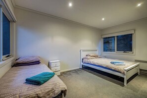 Un dormitorio con dos camas individuales, una mesita de noche, una ventana y un radiador.