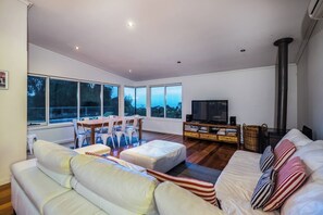 Una sala de estar moderna con sofá, reposapiés, televisor y chimenea.