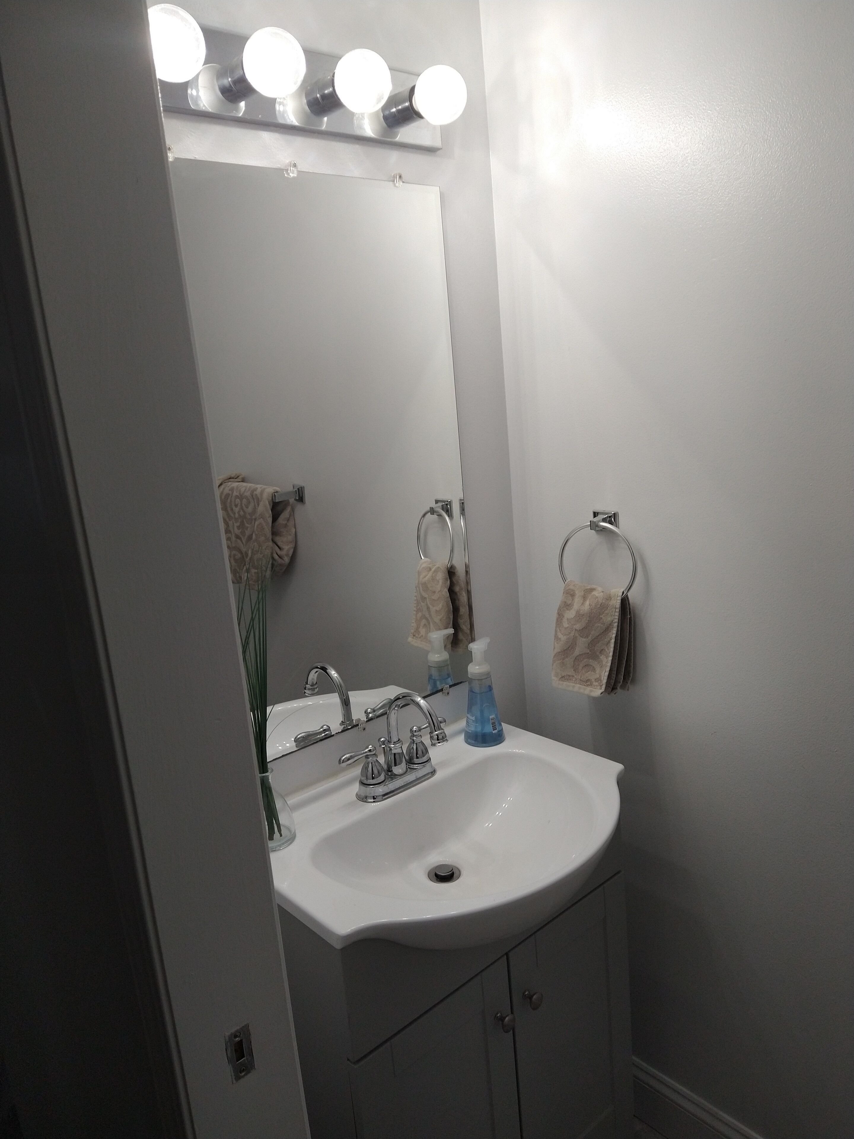 Une salle de bain avec un lavabo blanc, un miroir et un porte-serviettes.