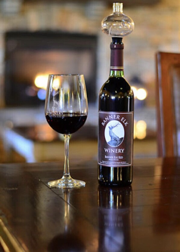 A bottle of wine and a glass on a wooden surface.