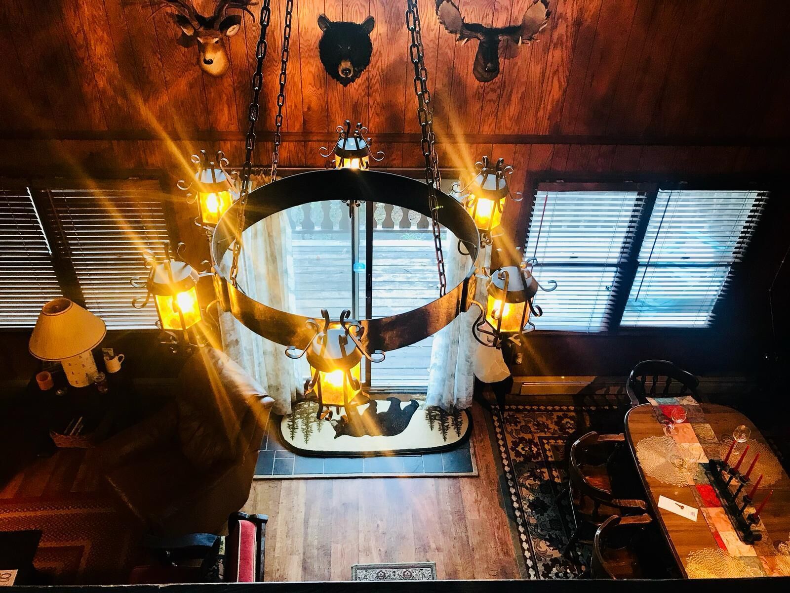 A cozy room with a central circular table, wooden walls, and a ceiling with mounted animal heads.