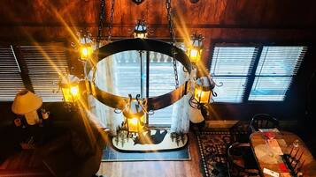 A cozy room with a central circular table, wooden walls, and a ceiling with mounted animal heads.