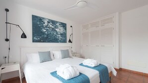 A hotel room with a large bed, two bedside lamps, a ceiling fan, a painting, and a wardrobe. - Private sun terraces with ocean/volcano views [I] (Icod de los Vinos)