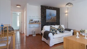 A modern living room with a white sofa, a wooden coffee table, and a stone accent wall. - Private sun terraces with ocean/volcano views [I] (Icod de los Vinos)