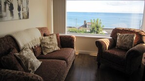 Un salon avec vue sur la mer, deux canapés à motifs et un tableau accroché au mur.