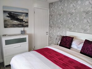 Une chambre à coucher avec un lit, une table de chevet, un bureau et une porte.