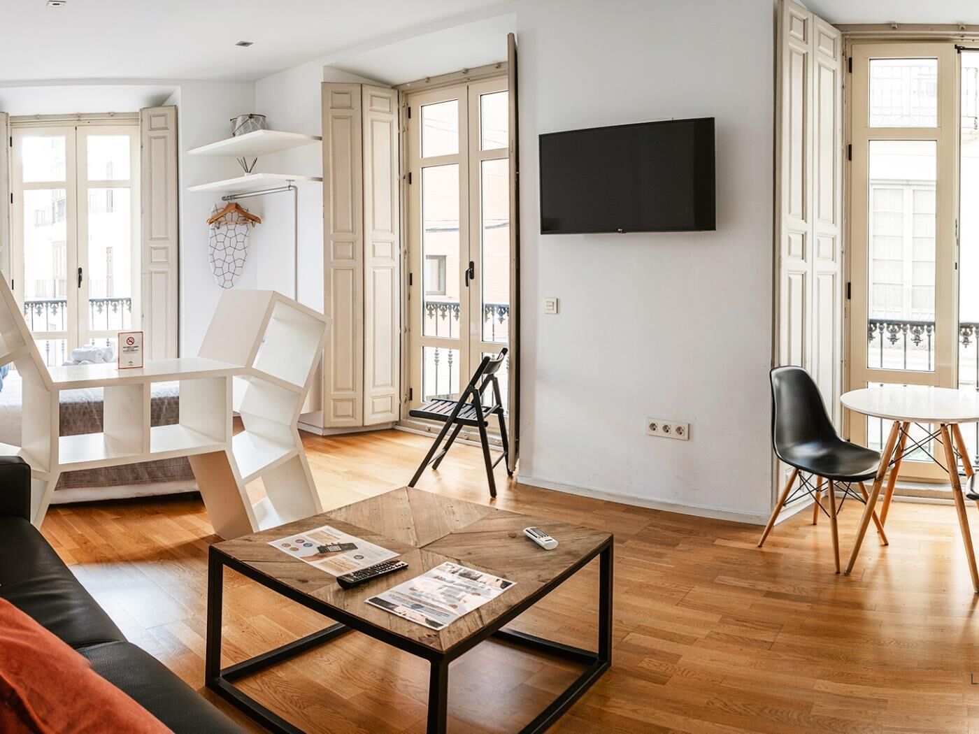 Een moderne woonkamer met een houten salontafel, een flatscreen televisie aan de muur en een balkon met uitzicht.