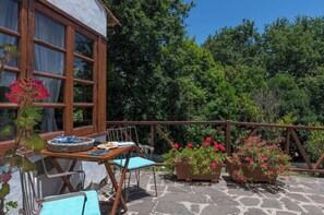 An outdoor patio with a table set for dining, surrounded by potted plants and a wooden railing. - GC0003 House with pool in Fontanales (Moya)