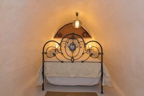A bed with a metal frame and a decorative headboard, a hanging light fixture above it, and a shelf with pottery. - GC0003 House with pool in Fontanales (Moya)