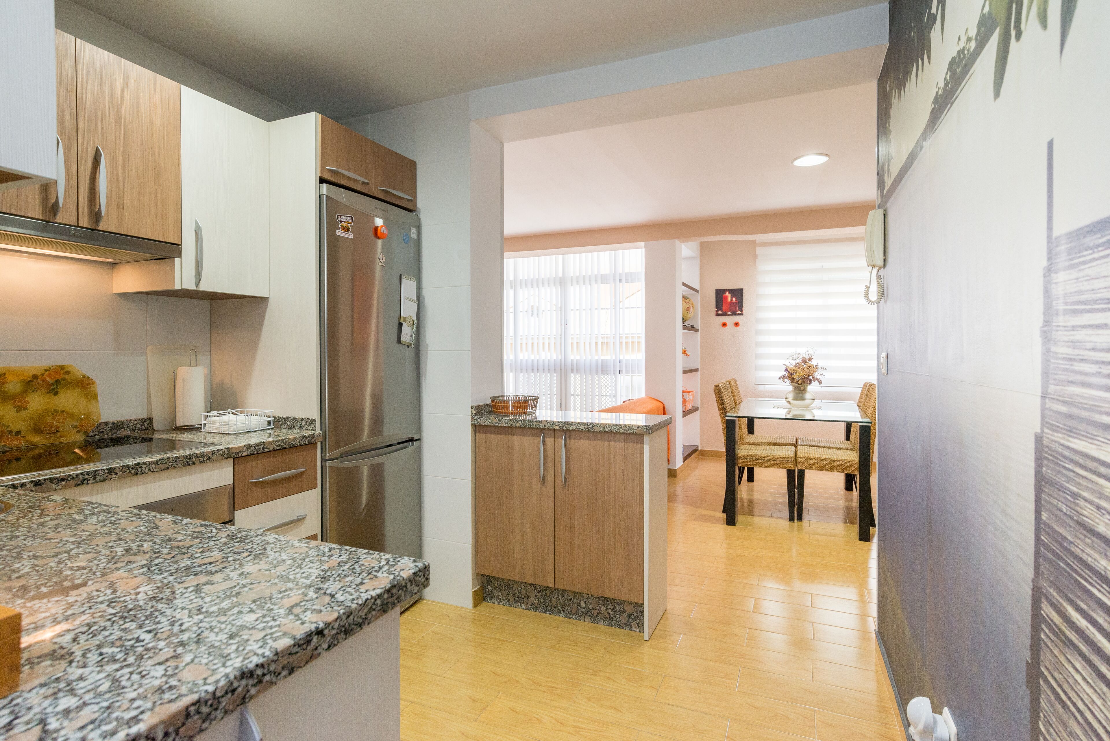 Una cocina moderna con encimeras de granito, electrodomésticos de acero inoxidable y armarios de madera.