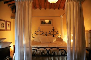 Une chambre à coucher avec un lit, des rideaux blancs et un luminaire au plafond.