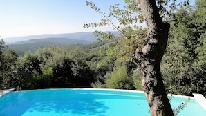 Une piscine d’eau cristalline, entourée d’une végétation luxuriante et dominée par un paysage montagneux.