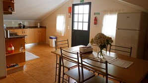 A kitchen with wooden cabinets, a dining table with chairs, a refrigerator, and a window with curtains. - Guest Apartment in Santana (Santana)