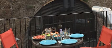 An outdoor dining area with a brick wall and a train passing overhead.
