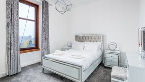 A bedroom with a bed, nightstands, a dresser, and a window with curtains. - Claymore Apartment, Brook Street, central Broughty Ferry, Dundee (Dundee)
