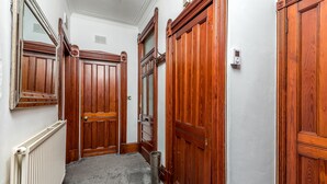 A hallway with wooden doors, a radiator, and a trash can. - Claymore Apartment, Brook Street, central Broughty Ferry, Dundee (Dundee)