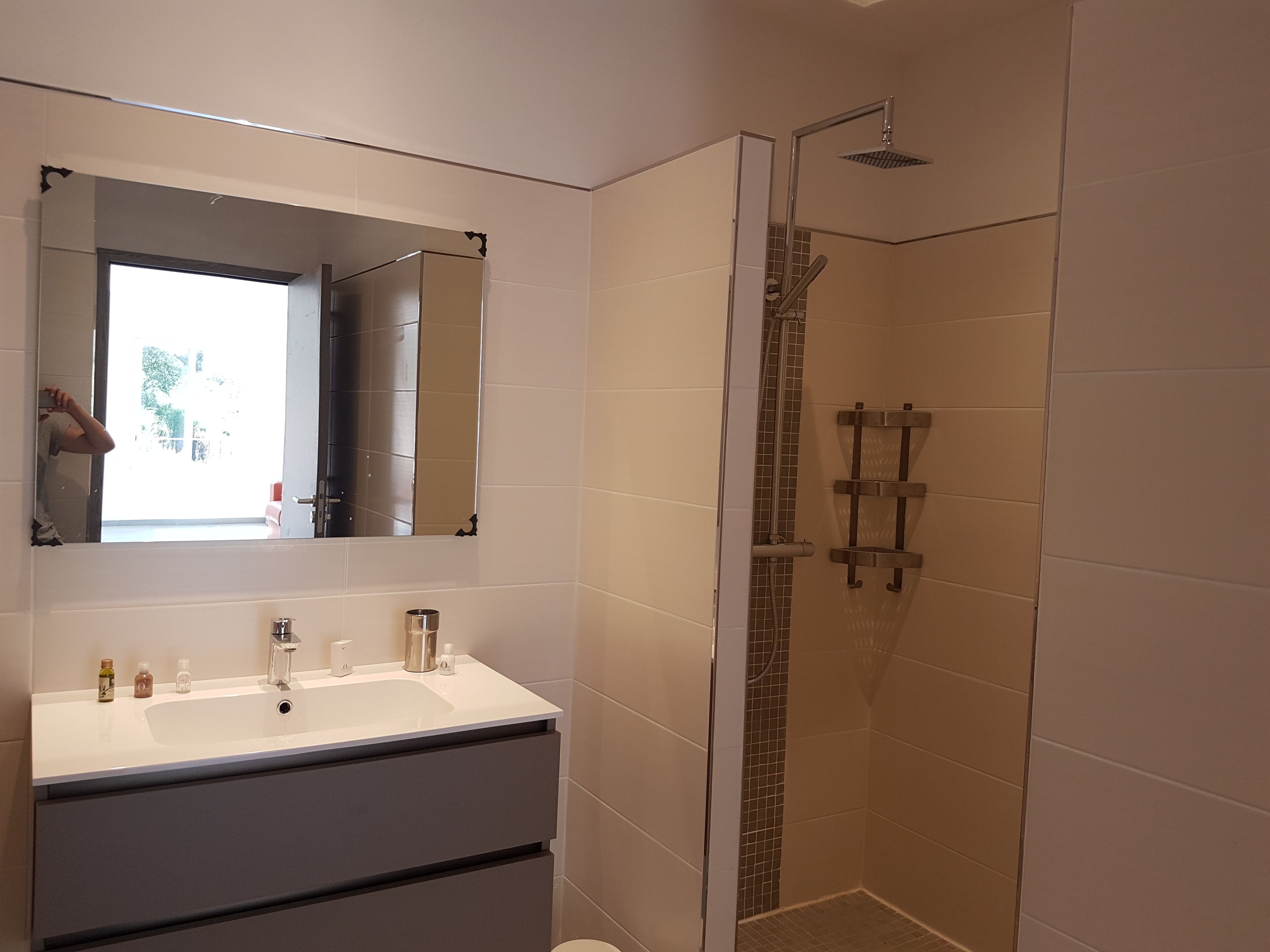 Une salle de bain avec un lavabo blanc, un miroir et une douche.