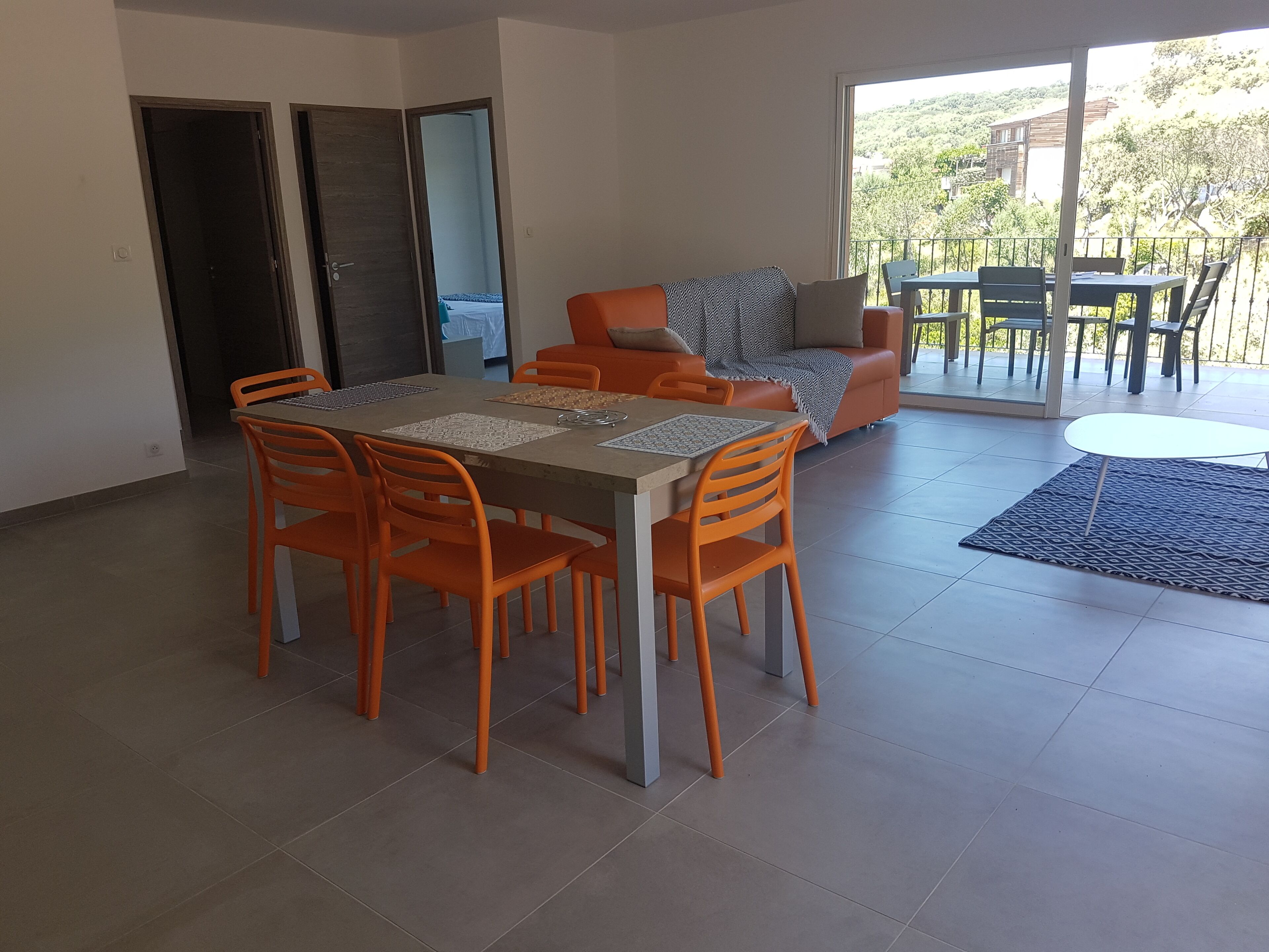 A dining area with a table and chairs, a sofa, and a view of the outdoors.