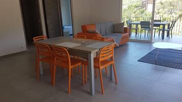 A dining area with a table and chairs, a sofa, and a view of the outdoors.