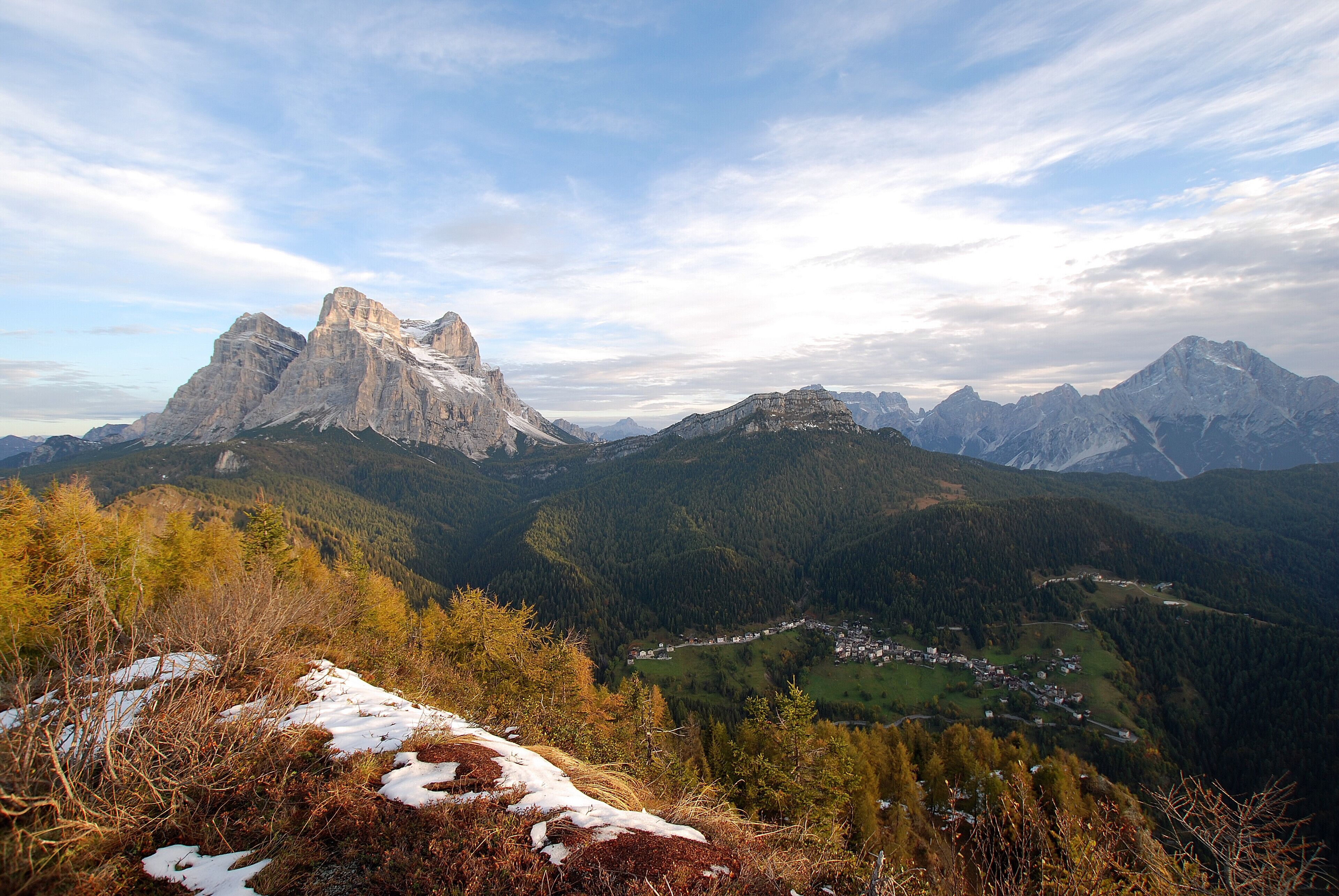 A mountainous landscape with a prominent peak, a valley with a small settlement, and a mix of forested areas.