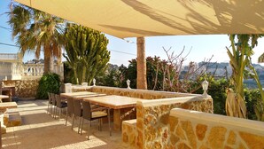 An outdoor patio with a table and chairs, surrounded by cacti and palm trees, overlooking a cityscape. - Villa Romeo Calpe for groups and large families with 2 pools (Calpe)